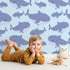 Lovely child standing in front of Whimsy Tots Whale Shark Wiggles Wallpaper in Sky Blue with shark, whale shark, spot, sea in design. Lovely child standing in front of Whimsy Tots Whale Shark Wiggles Wallpaper in Sky Blue with shark, whale shark, spot, sea in design.