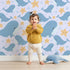 Lovely child standing in front of Whimsy Tots Starry Whale Friends Wallpaper in Lilac Lavender with whale, starfish, bubble, dot in design. Lovely child standing in front of Whimsy Tots Starry Whale Friends Wallpaper in Lilac Lavender with whale, starfish, bubble, dot in design.