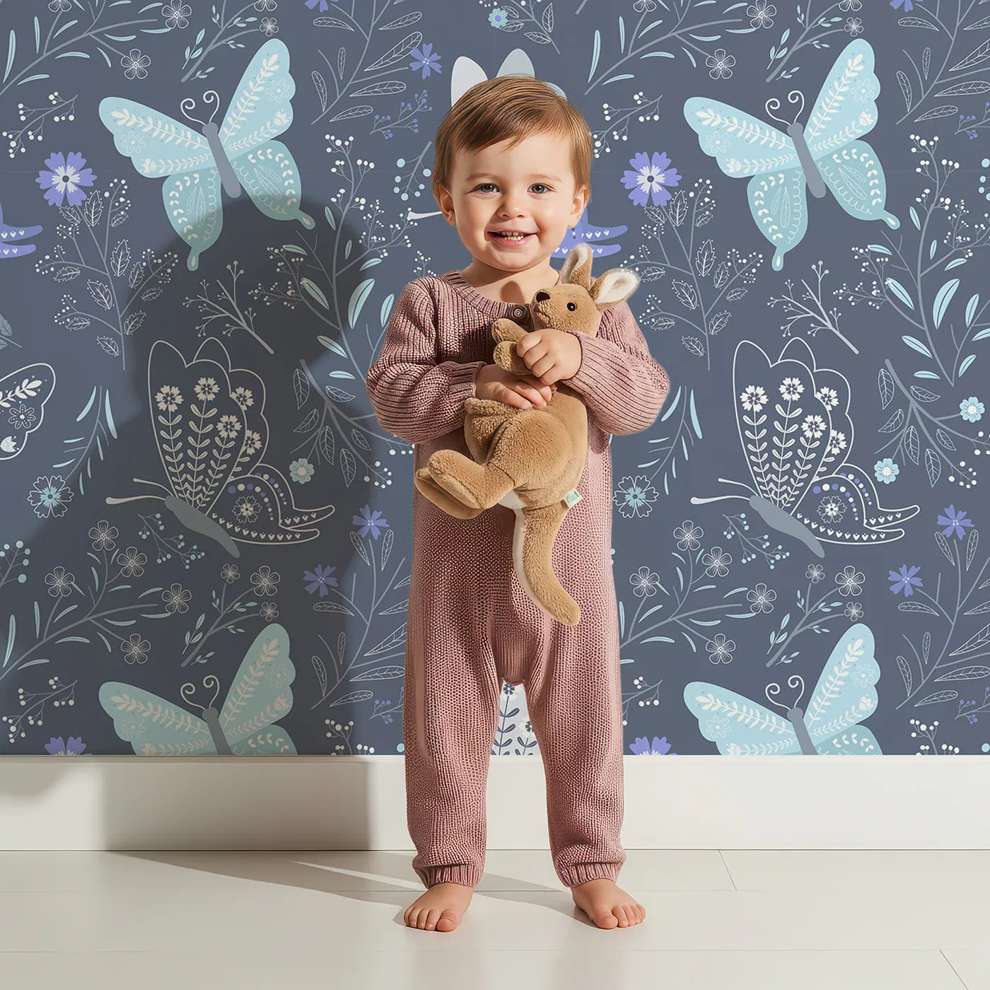 Lovely child standing in front of Whimsy Tots Wild Bloom Butterfly Wallpaper in Twilight Blue with butterfly, flower, leaf, vine in design.