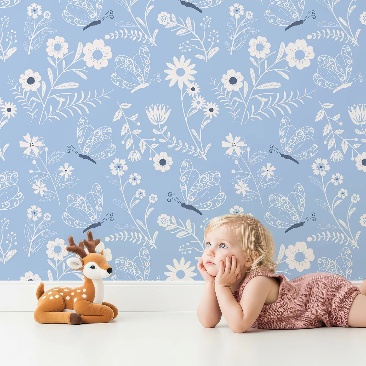 Lovely child standing in front of Whimsy Tots Floral Flutter Butterfly Wallpaper in Powder Blue with butterfly, flower, leaf in design.
