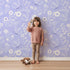 Lovely child standing in front of Whimsy Tots Floral Flutter Butterfly Wallpaper in Lavender Mist with butterfly, flower, leaf in design. Lovely child standing in front of Whimsy Tots Floral Flutter Butterfly Wallpaper in Lavender Mist with butterfly, flower, leaf in design.