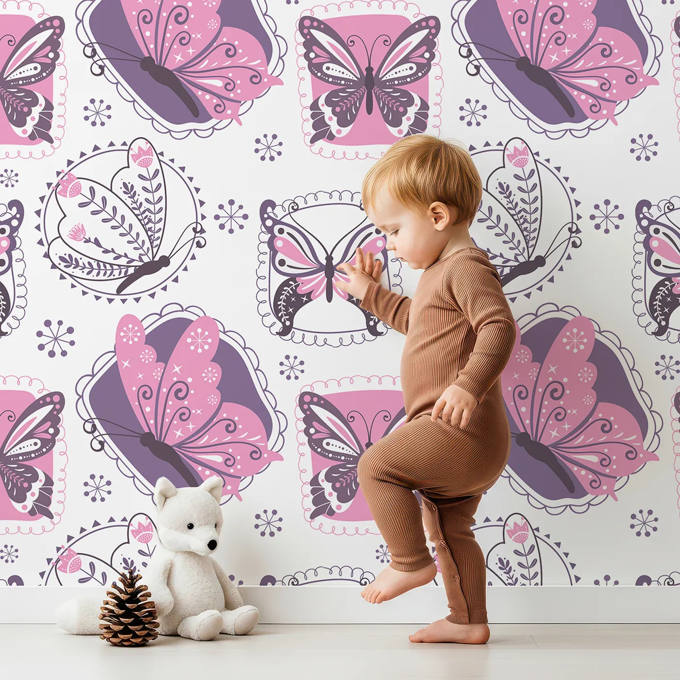 Lovely child standing in front of Whimsy Tots Patchwork Garden Butterfly Wallpaper in Pink with butterfly, flower, leaf, patch, sparkle in design.
