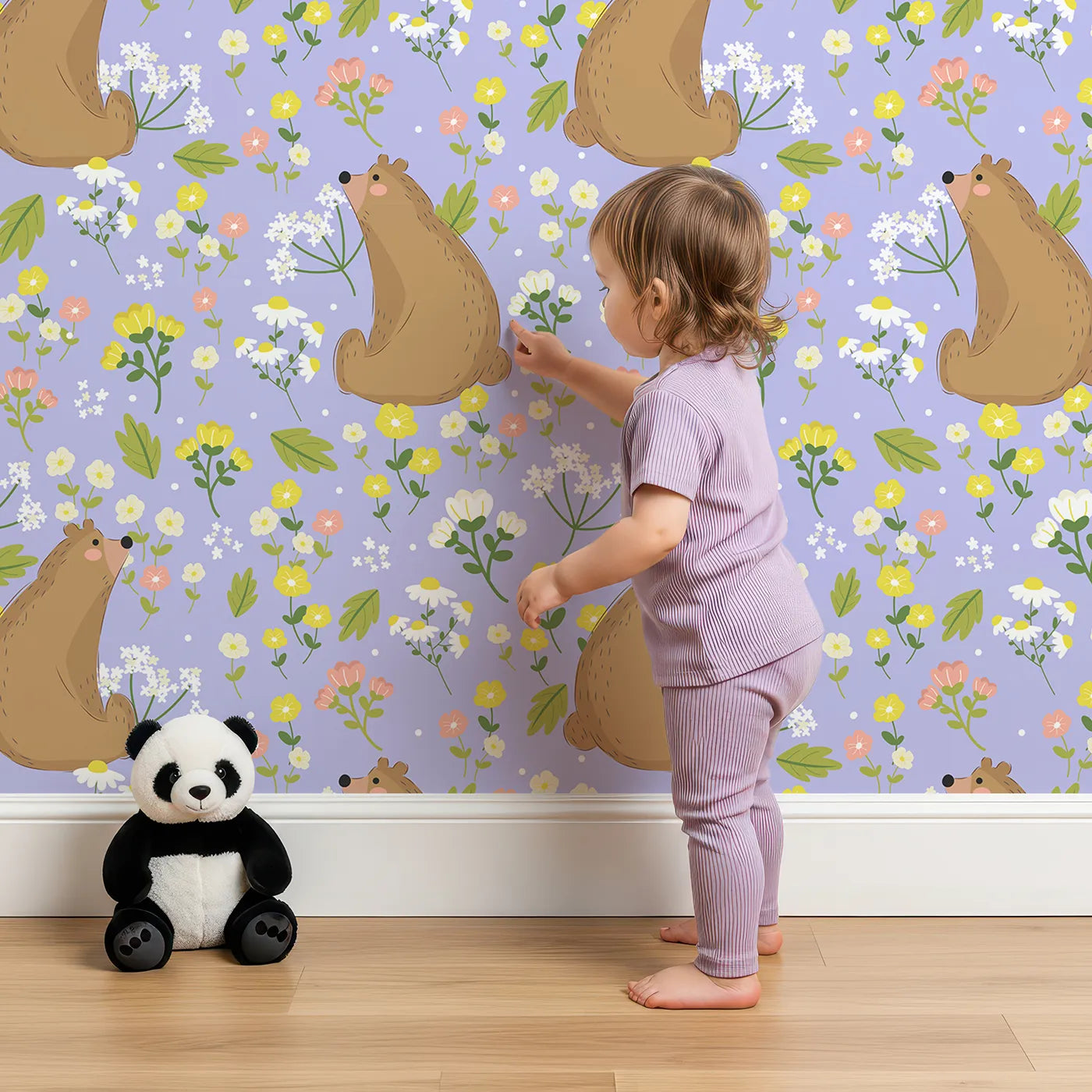 Lovely child standing in front of Whimsy Tots Blossom Bear Meadow Wallpaper in Lavender Mist with bear, flower, leaf, blossom in design.