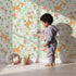 Lovely child standing in front of Whimsy Tots Spring Fawn Dance Wallpaper in Mint Meadow Green with deer, flower, meadow, tulip in design. Lovely child standing in front of Whimsy Tots Spring Fawn Dance Wallpaper in Mint Meadow Green with deer, flower, meadow, tulip in design.