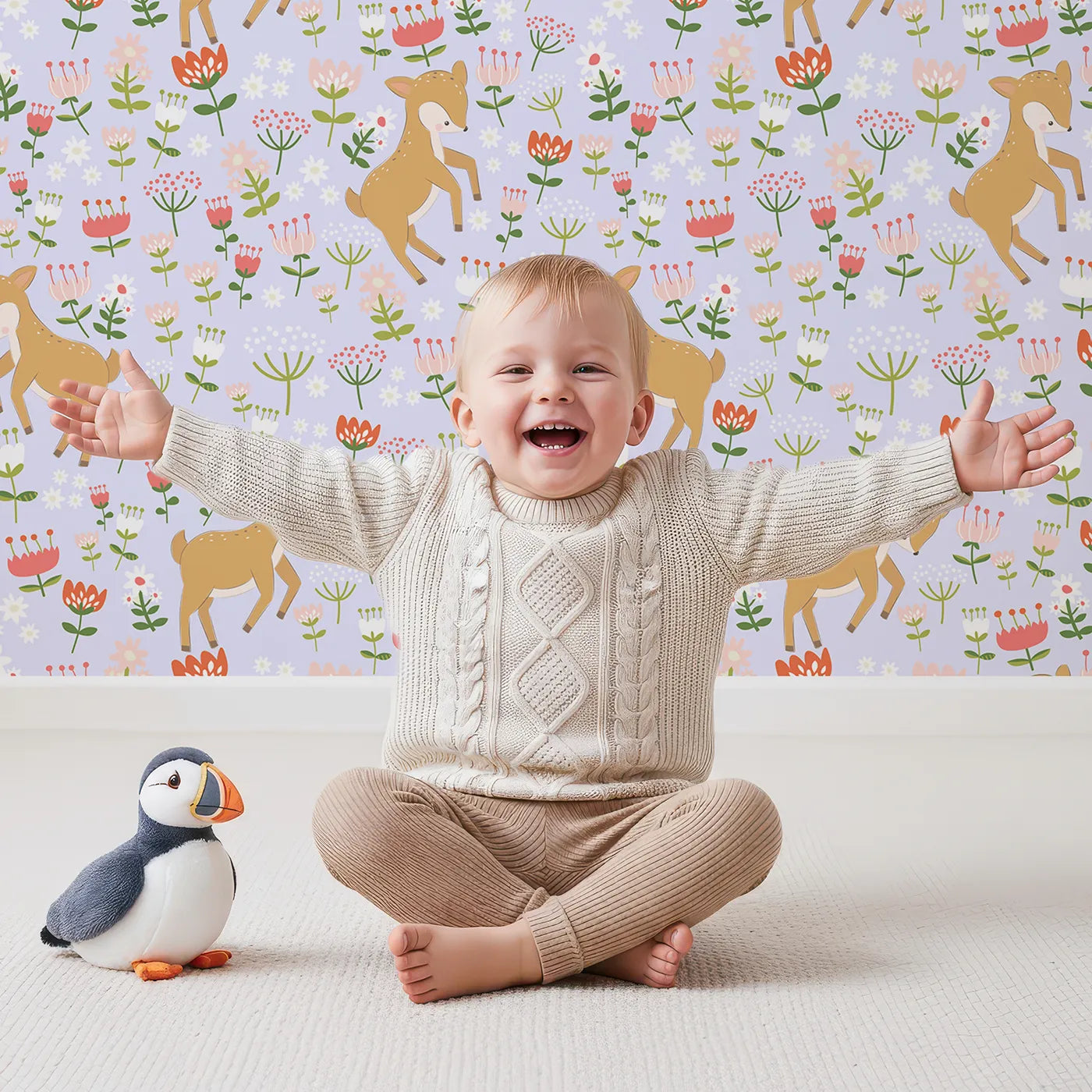 Lovely child standing in front of Whimsy Tots Spring Fawn Dance Wallpaper in Lavender Mist with deer, flower, meadow, tulip in design.