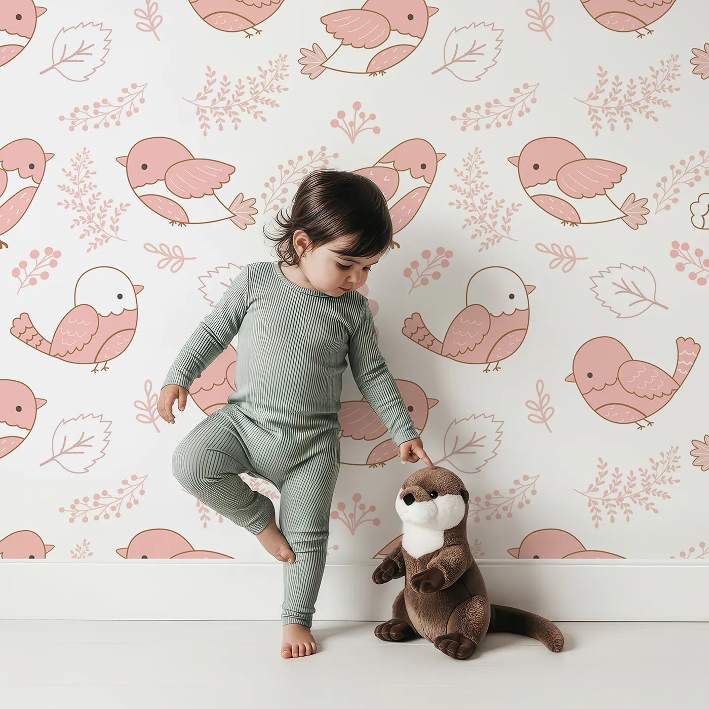 Lovely child standing in front of Whimsy Tots Tweetheart Meadow Wallpaper in Blush Pink with bird, leaf, flower, berry in design.