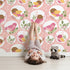 Lovely child standing in front of Whimsy Tots Garden Songbird Parade Wallpaper in Blush Pink with bird, branch, leaf, berry in design. Lovely child standing in front of Whimsy Tots Garden Songbird Parade Wallpaper in Blush Pink with bird, branch, leaf, berry in design.