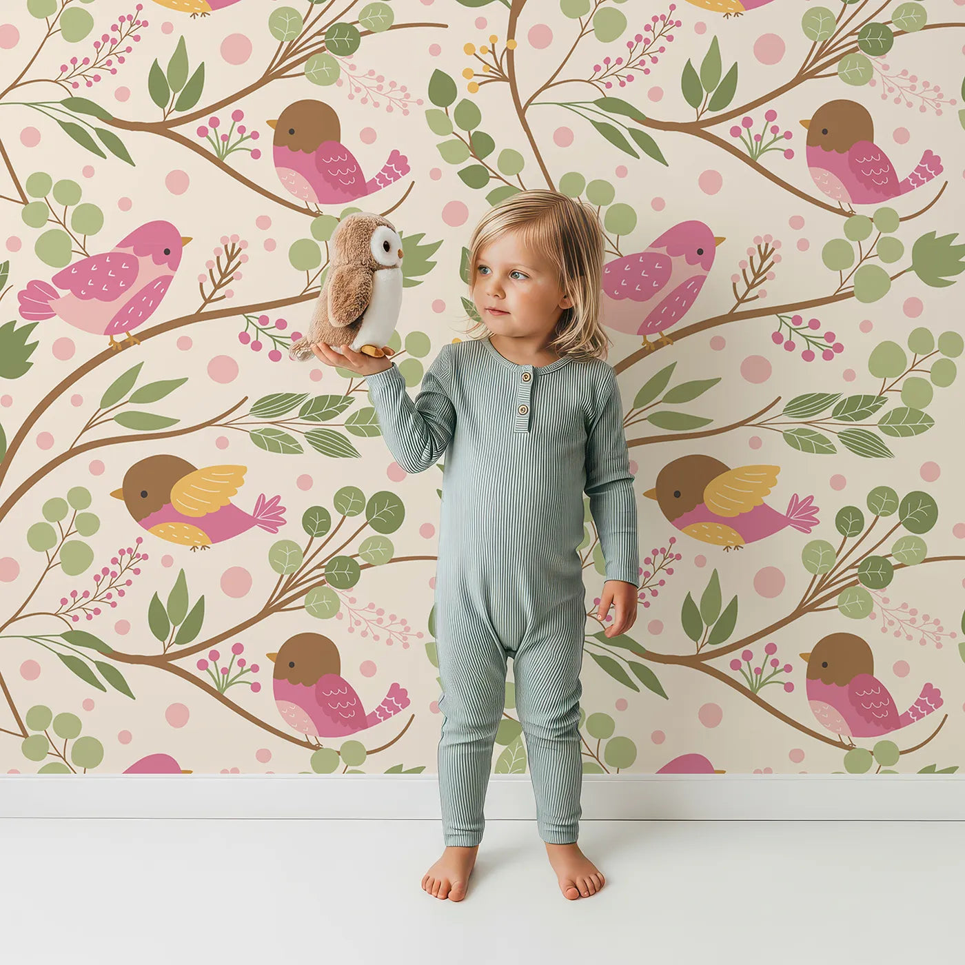 Lovely child standing in front of Whimsy Tots Blossom Branch Birds Wallpaper in Cream with bird, branch, berry, leaf in design.