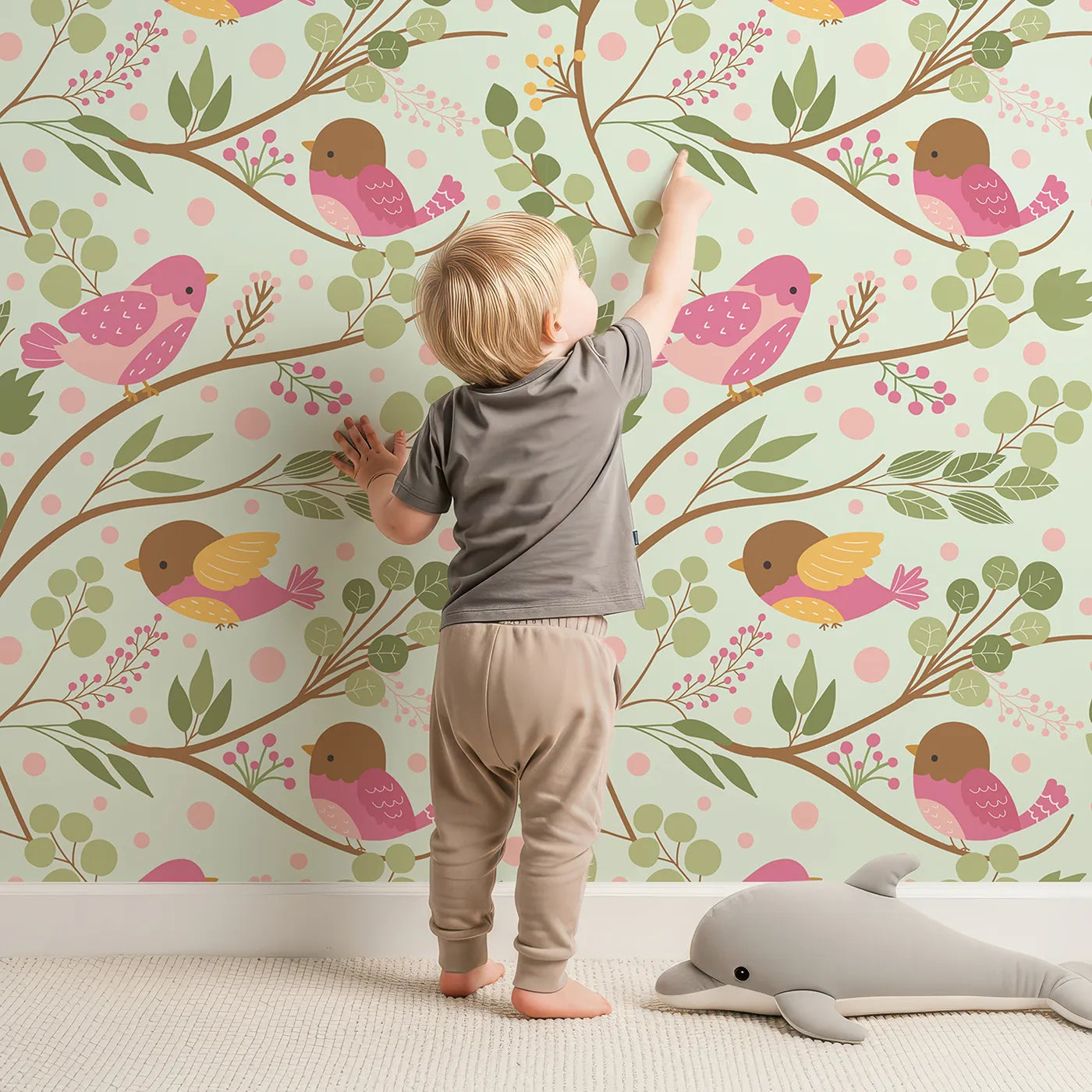 Lovely child standing in front of Whimsy Tots Blossom Branch Birds Wallpaper in Mint Green with bird, berry, leaf, branch in design.