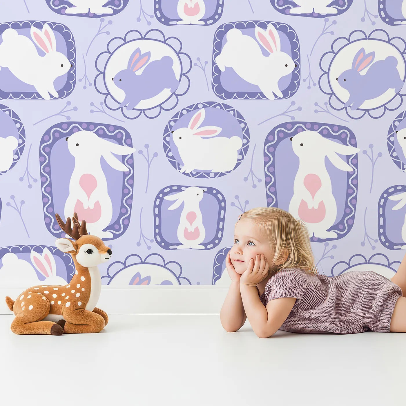 Lovely child standing in front of Whimsy Tots Framed Bunny Whimsy Wallpaper in Lavender with rabbit, frame, bunny, flower, twig in design.