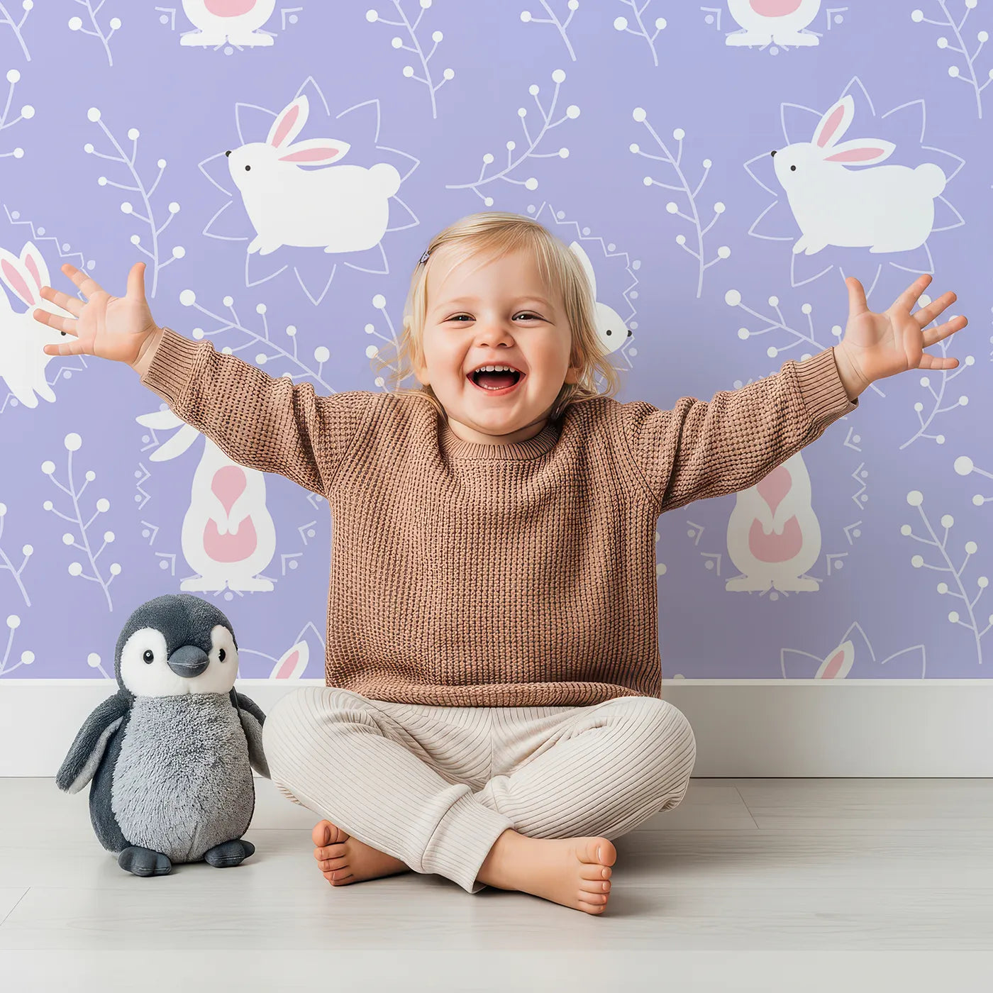 Lovely child standing in front of Whimsy Tots Tribal Bunny Sprigs Wallpaper in Lavender with rabbit, bunny, sprig, leaf, tribal motif in design.