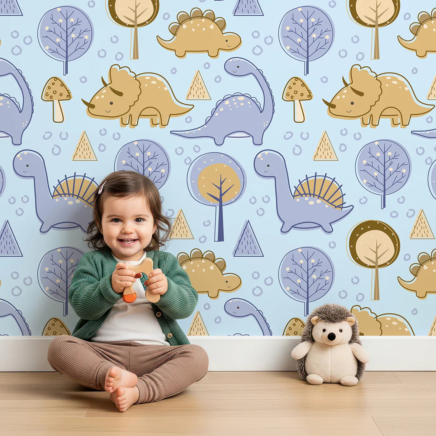 Lovely child standing in front of Whimsy Tots Jurassic Forest Friends Wallpaper in Sky Blue with dinosaur, tree, triangle, dino, forest in design.