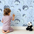 Lovely child standing in front of Whimsy Tots Dino Circle Parade Wallpaper in Sky Blue with dinosaur, flower, heart, circle in design. Lovely child standing in front of Whimsy Tots Dino Circle Parade Wallpaper in Sky Blue with dinosaur, flower, heart, circle in design.