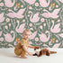 Lovely child standing in front of Whimsy Tots Starlit Swan Ballet Wallpaper in Sage Green with swan, crown, flower, bow, leaf in design. Lovely child standing in front of Whimsy Tots Starlit Swan Ballet Wallpaper in Sage Green with swan, crown, flower, bow, leaf in design.