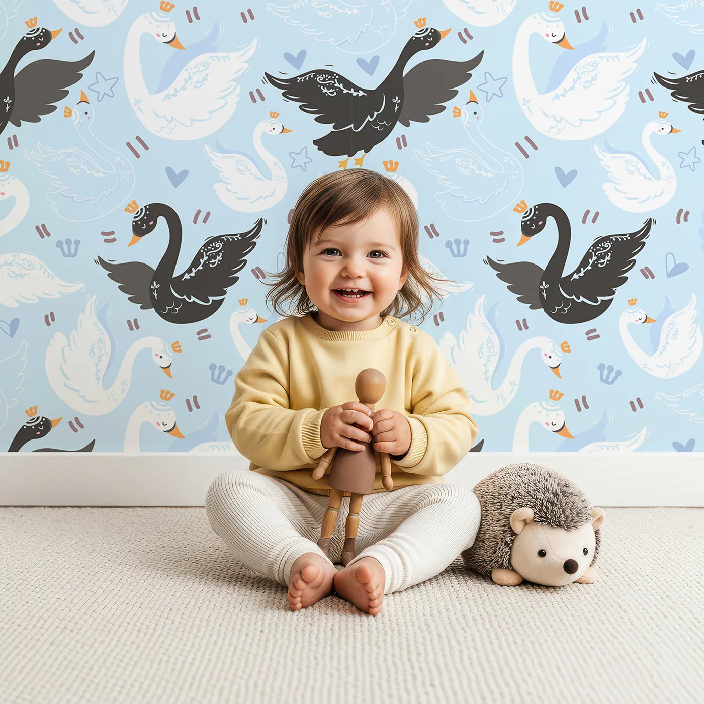 Lovely child standing in front of Whimsy Tots Royal Swan Parade Wallpaper in Sky Blue with swan, crown, heart, star, wing in design.