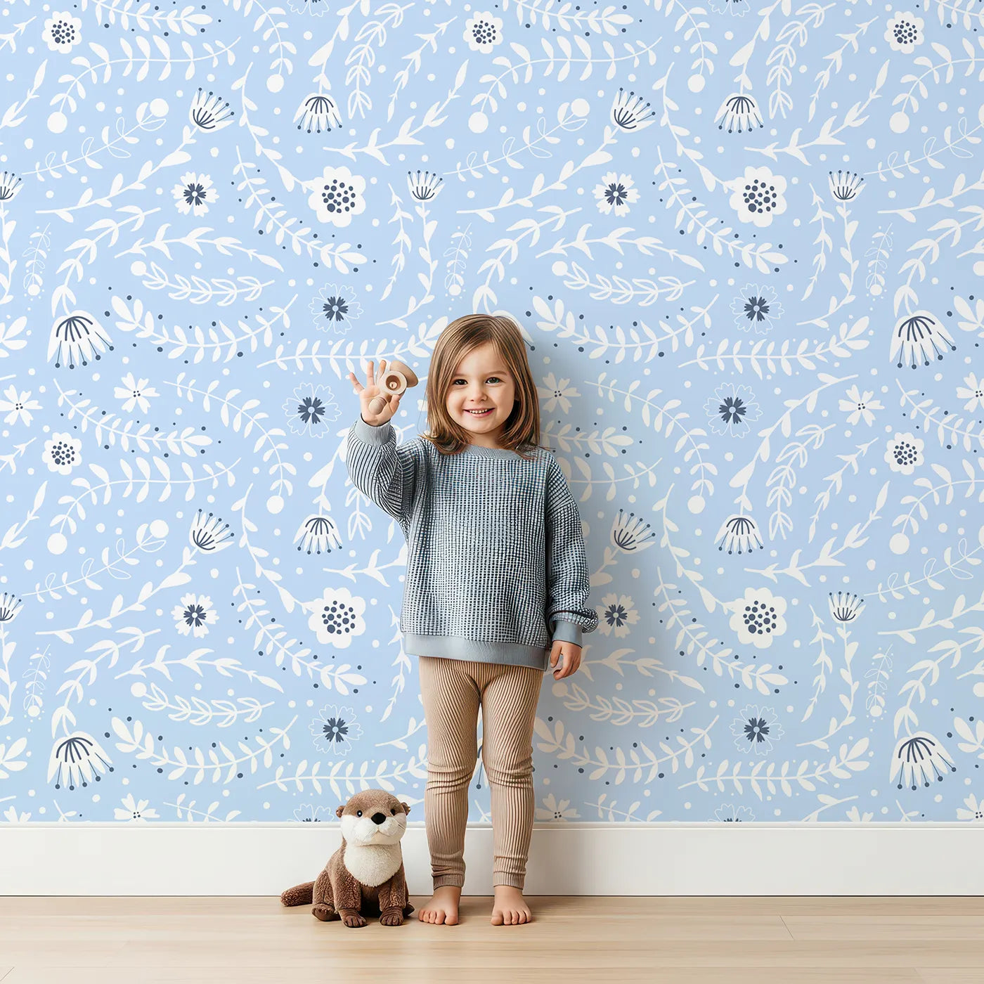 Lovely child standing in front of Whimsy Tots Spring Meadow Whispers Wallpaper in Sky Blue with flower, vine, leaf, dot in design.