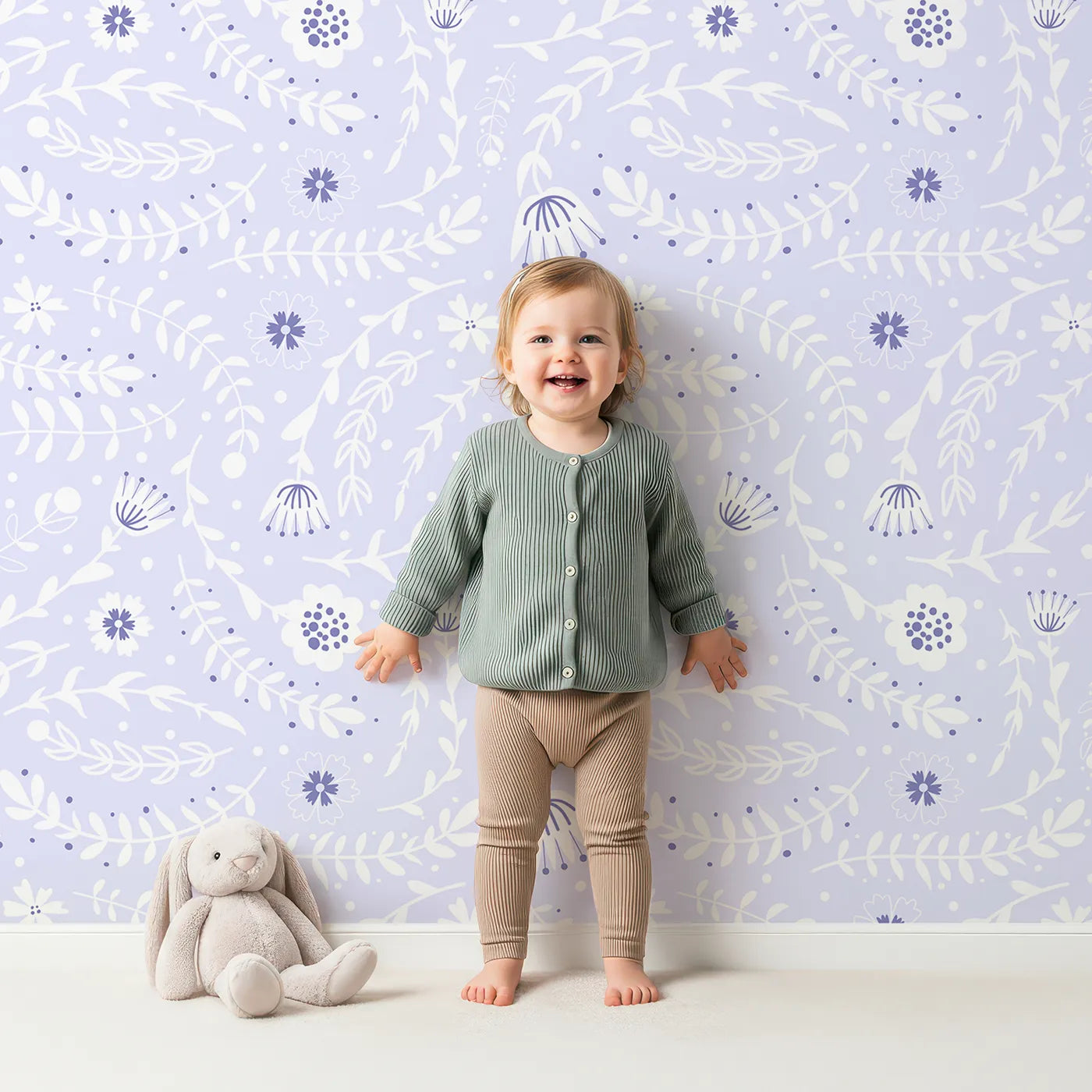 Lovely child standing in front of Whimsy Tots Spring Meadow Whispers Wallpaper in Lavender with flower, vine, leaf, dot in design.