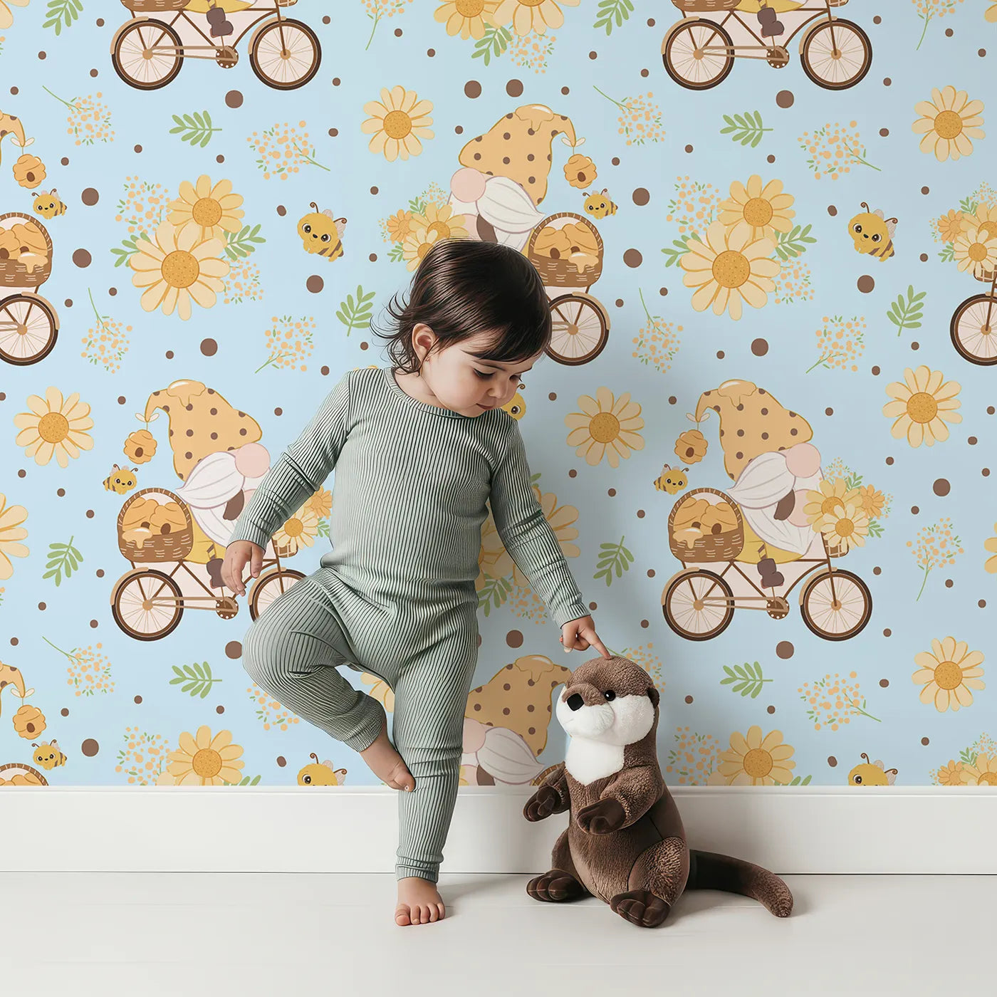 Lovely child standing in front of Whimsy Tots Honeybee Gnome Parade Wallpaper in Sky Blue with gnome, bee, flower, bicycle in design.