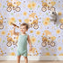 Lovely child standing in front of Whimsy Tots Honeybee Gnome Parade Wallpaper in Lavender Breeze with gnome, bee, flower, bicycle in design. Lovely child standing in front of Whimsy Tots Honeybee Gnome Parade Wallpaper in Lavender Breeze with gnome, bee, flower, bicycle in design.