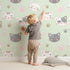 Lovely child standing in front of Whimsy Tots Whisker Wink Kitty Wallpaper in Mint Green with cat, pawprint, whisker, smile in design. Lovely child standing in front of Whimsy Tots Whisker Wink Kitty Wallpaper in Mint Green with cat, pawprint, whisker, smile in design.