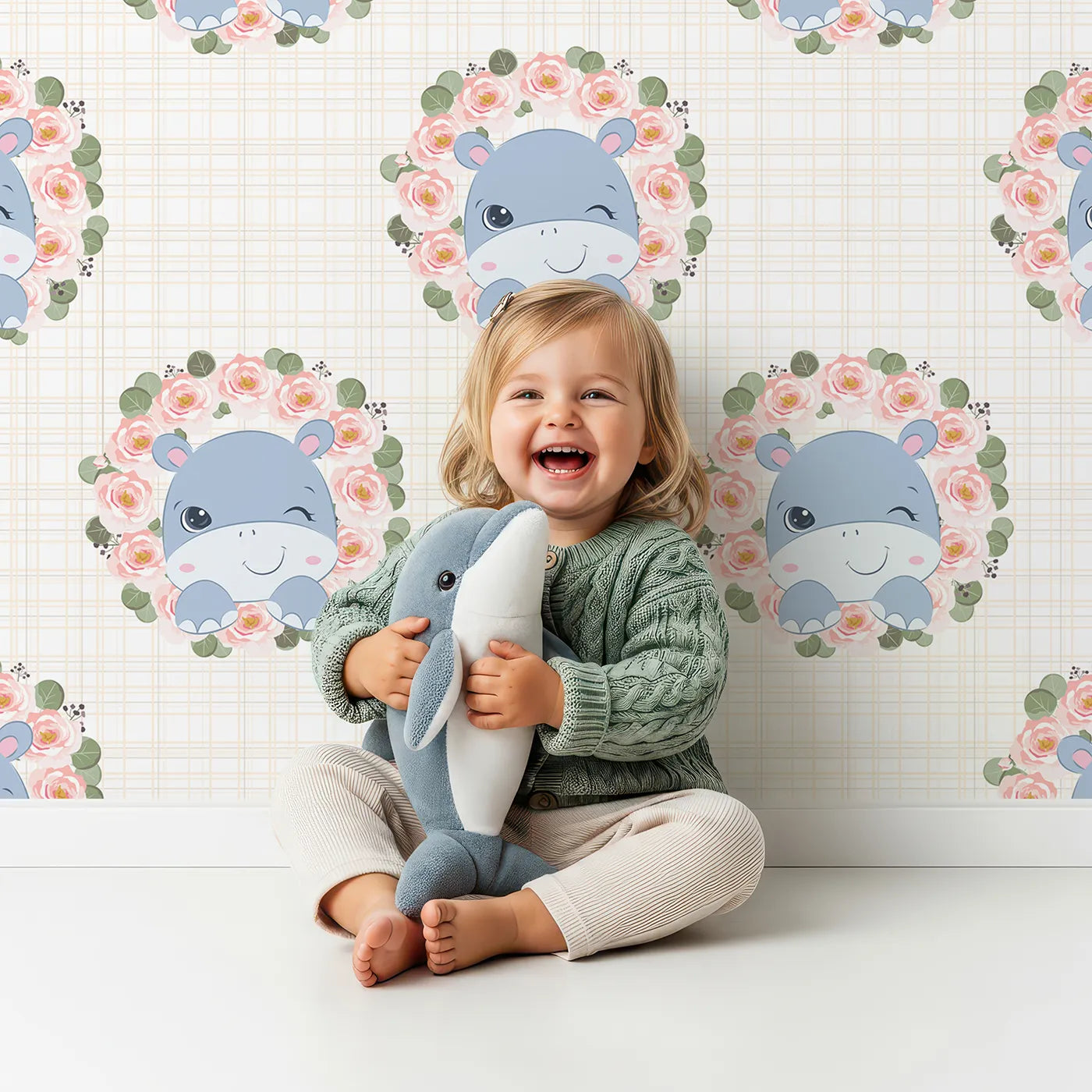Lovely child standing in front of Whimsy Tots Blossom Hippo Winks Wallpaper in Buttercream Plaid with hippo, flower, wreath, rose in design.