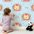 Lovely child standing in front of Whimsy Tots Little Lion Blossom Parade Wallpaper in Sky Blue with lion, flower, wreath, leaf, blossom in design. Lovely child standing in front of Whimsy Tots Little Lion Blossom Parade Wallpaper in Sky Blue with lion, flower, wreath, leaf, blossom in design.