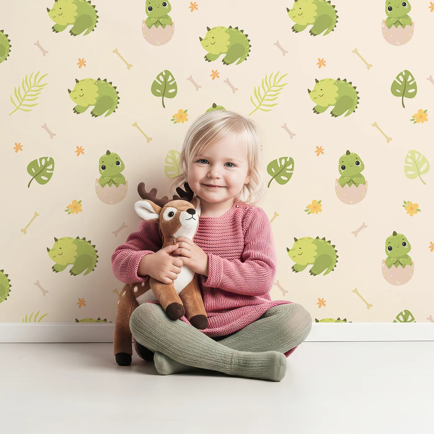 Lovely child standing in front of Whimsy Tots Hatching Dino Friends Wallpaper in Warm Cream with dinosaur, egg, leaf, flower, bone in design.
