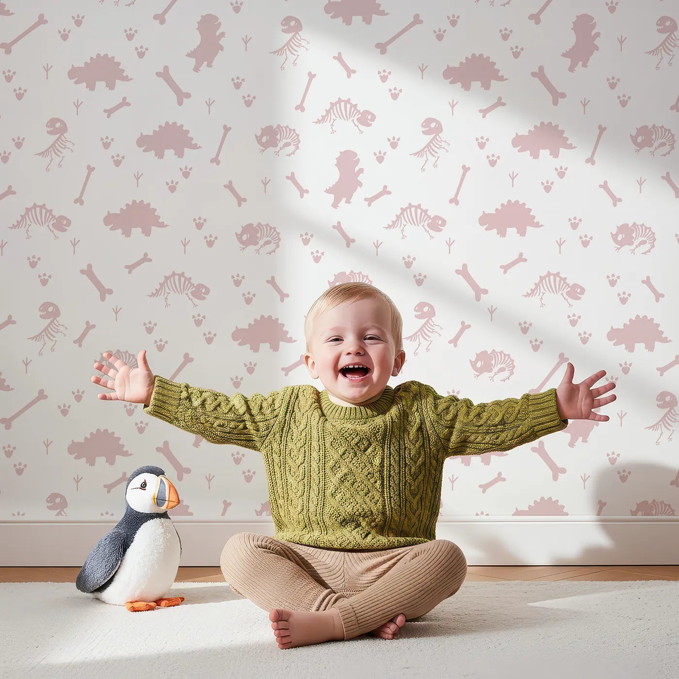 Lovely child standing in front of Whimsy Tots Fossil Roar Parade Wallpaper in Dusty Rose Pink with dinosaur, skeleton, bone, footprint in design.