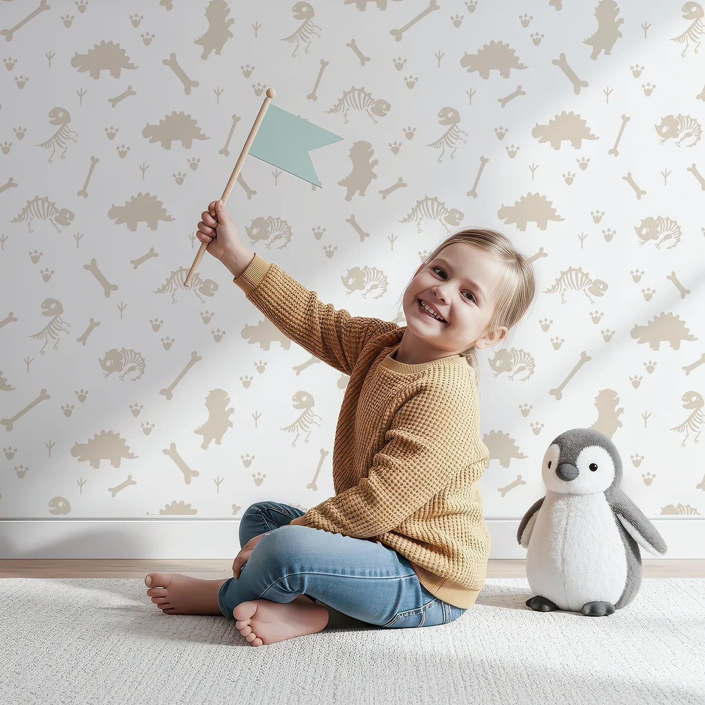 Lovely child standing in front of Whimsy Tots Fossil Roar Parade Wallpaper in Soft Taupe Beige with dinosaur, skeleton, bone, footprint in design.