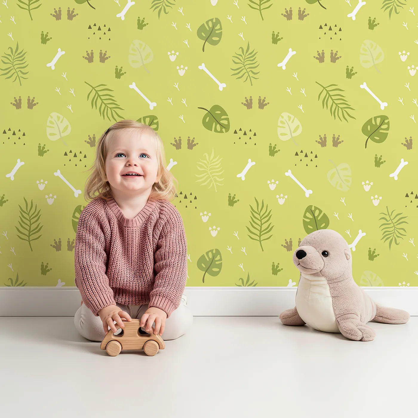 Lovely child standing in front of Whimsy Tots Jungle Fossil Tracks Wallpaper in Leafy Lime with bone, footprint, leaf, track in design.