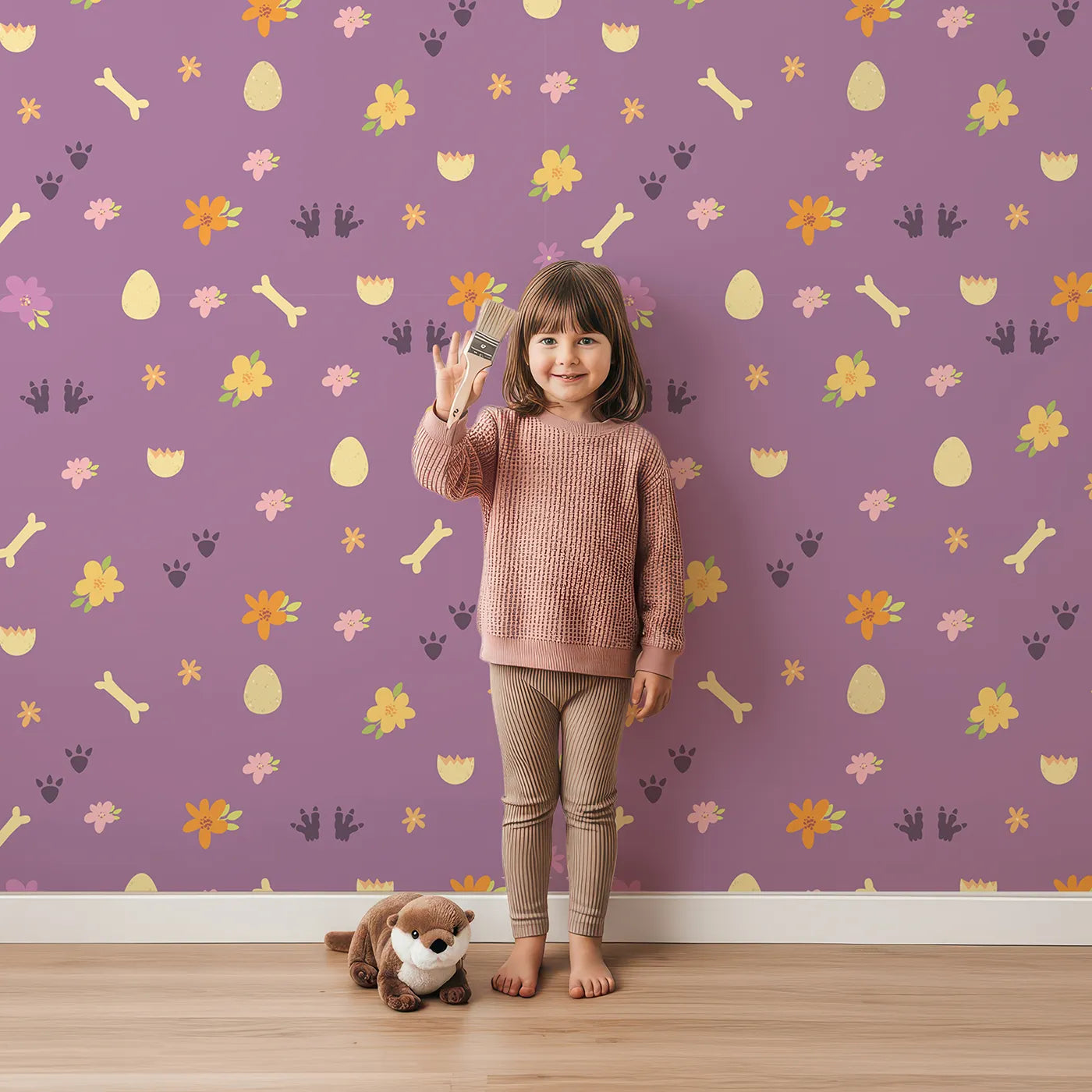 Lovely child standing in front of Whimsy Tots Dino Hatch Trail Wallpaper in Berry Bloom with egg, bone, flower, footprint in design.