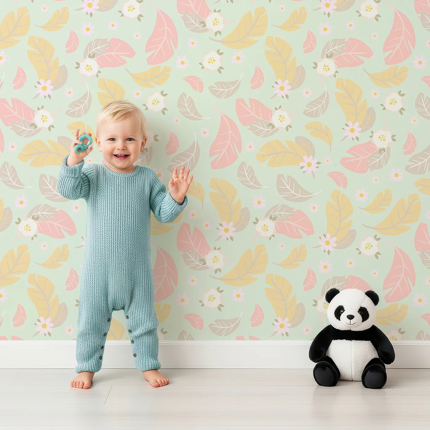 Lovely child standing in front of Whimsy Tots Floral Feather Drift Wallpaper in Mint Garden Green with feather, flower, blossom, leaf in design.