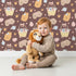 Lovely child standing in front of Whimsy Tots Blossom Basket Friends Wallpaper in Cocoa Blush Brown with fox, mouse, flower, basket, crown in design. Lovely child standing in front of Whimsy Tots Blossom Basket Friends Wallpaper in Cocoa Blush Brown with fox, mouse, flower, basket, crown in design.