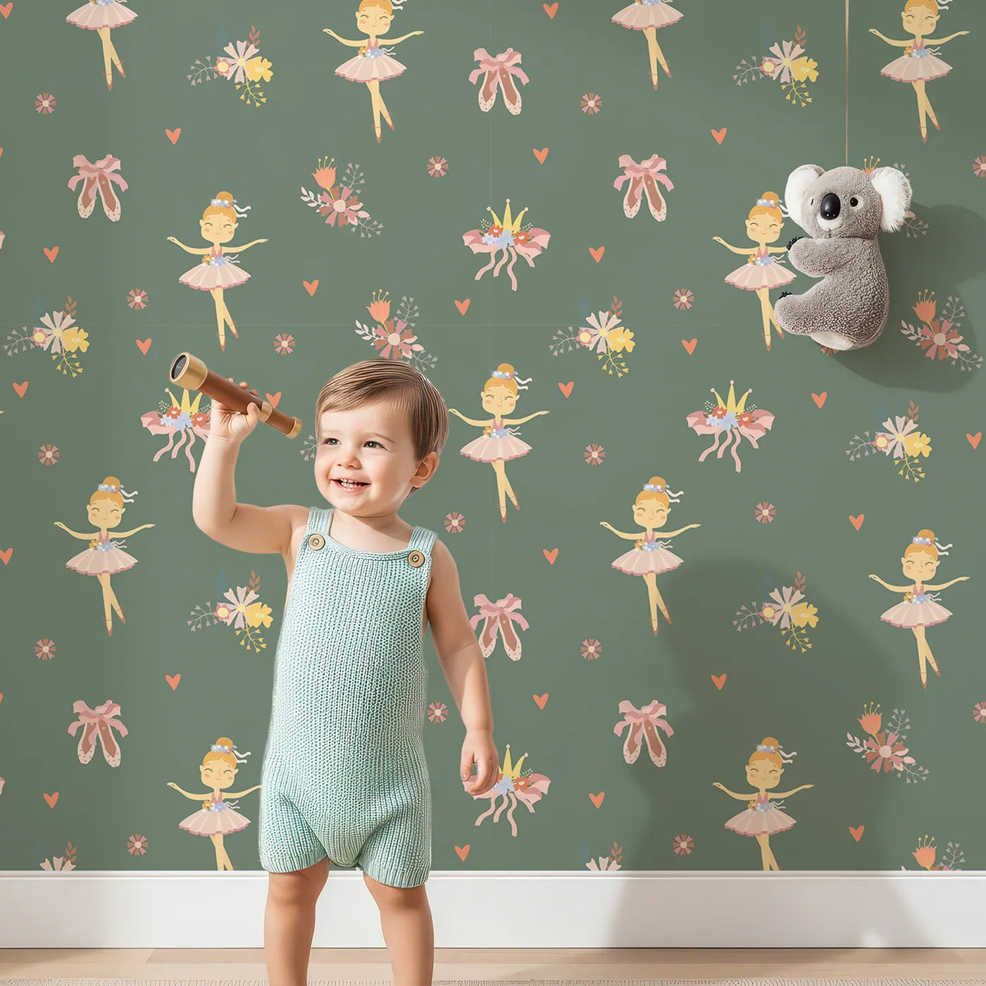Lovely child standing in front of Whimsy Tots Blush Ballerina Dreams Wallpaper in Forest Waltz Green with ballerina, crown, tutu, slipper, flower in design.