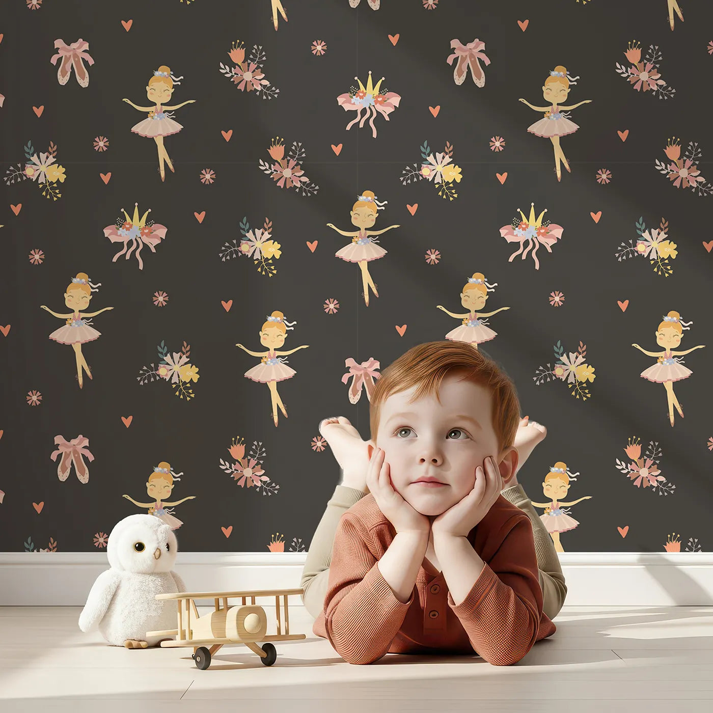 Lovely child standing in front of Whimsy Tots Blush Ballerina Dreams Wallpaper in Twilight Rehearsal with ballerina, crown, tutu, slipper, flower in design.