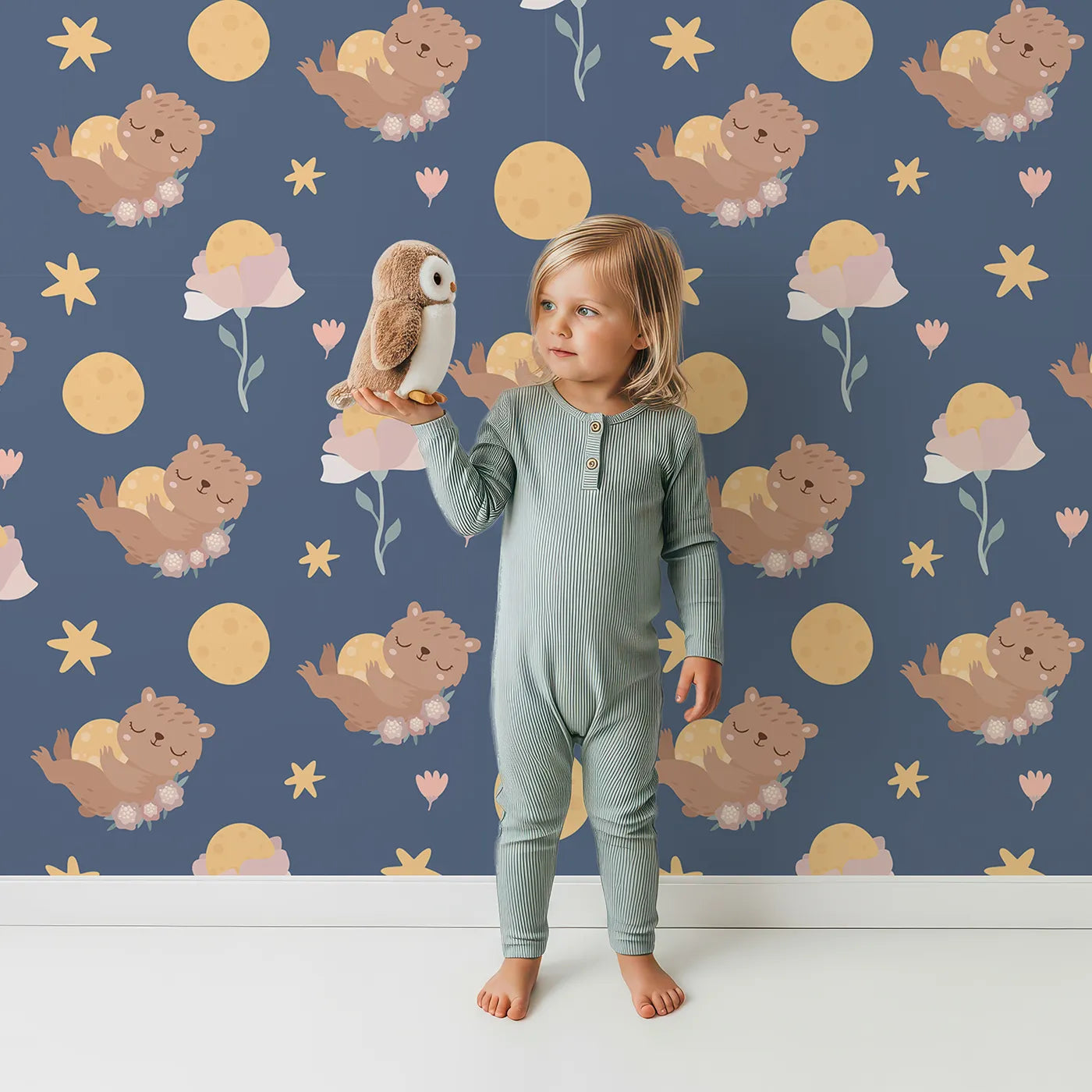 Lovely child standing in front of Whimsy Tots Moonlit Bear Dreams Wallpaper in Twilight Sky with bear, flower, moon, star in design.