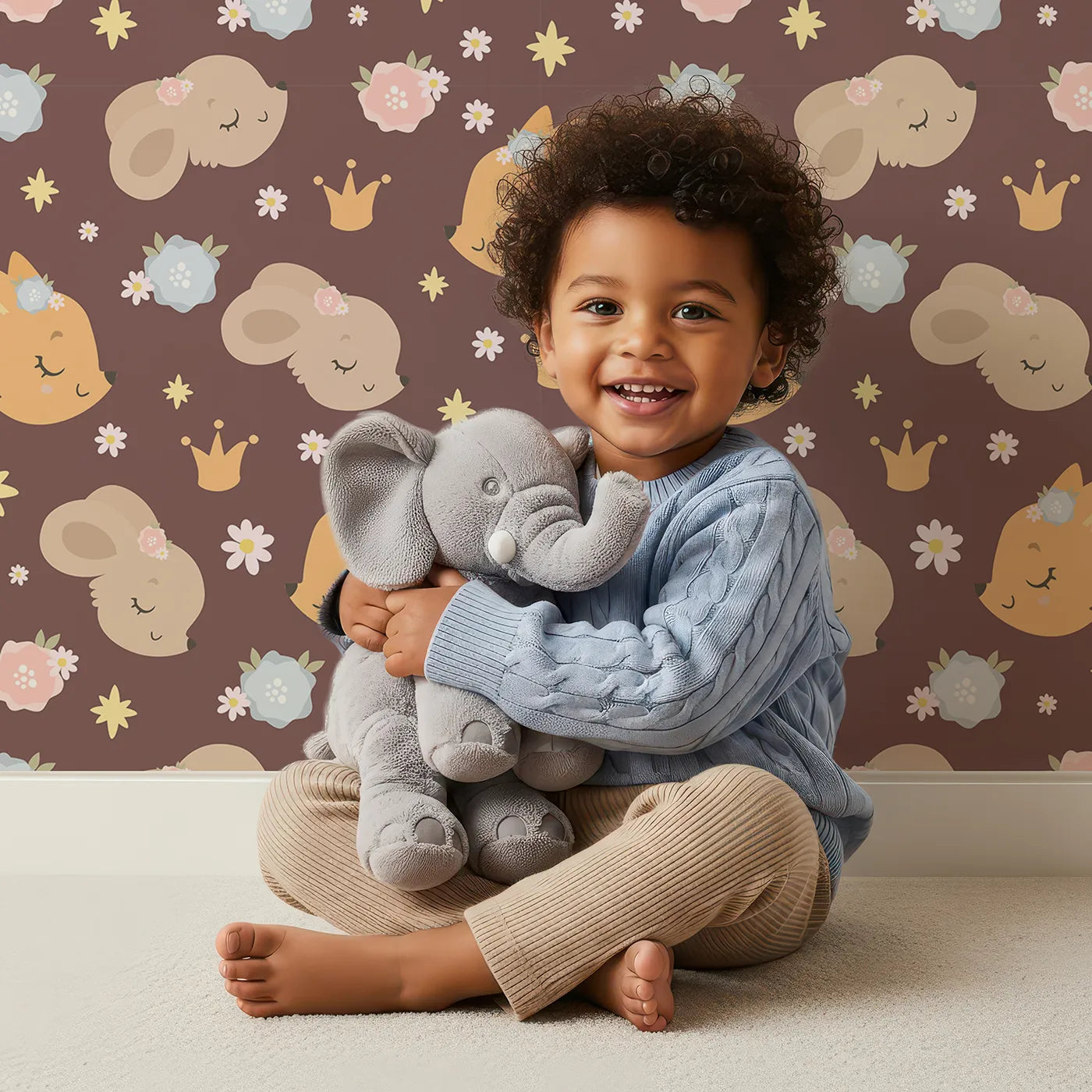 Lovely child standing in front of Whimsy Tots Royal Woodland Friends Wallpaper in Cocoa Crown Brown with fox, rabbit, bear, flower, crown, star in design.