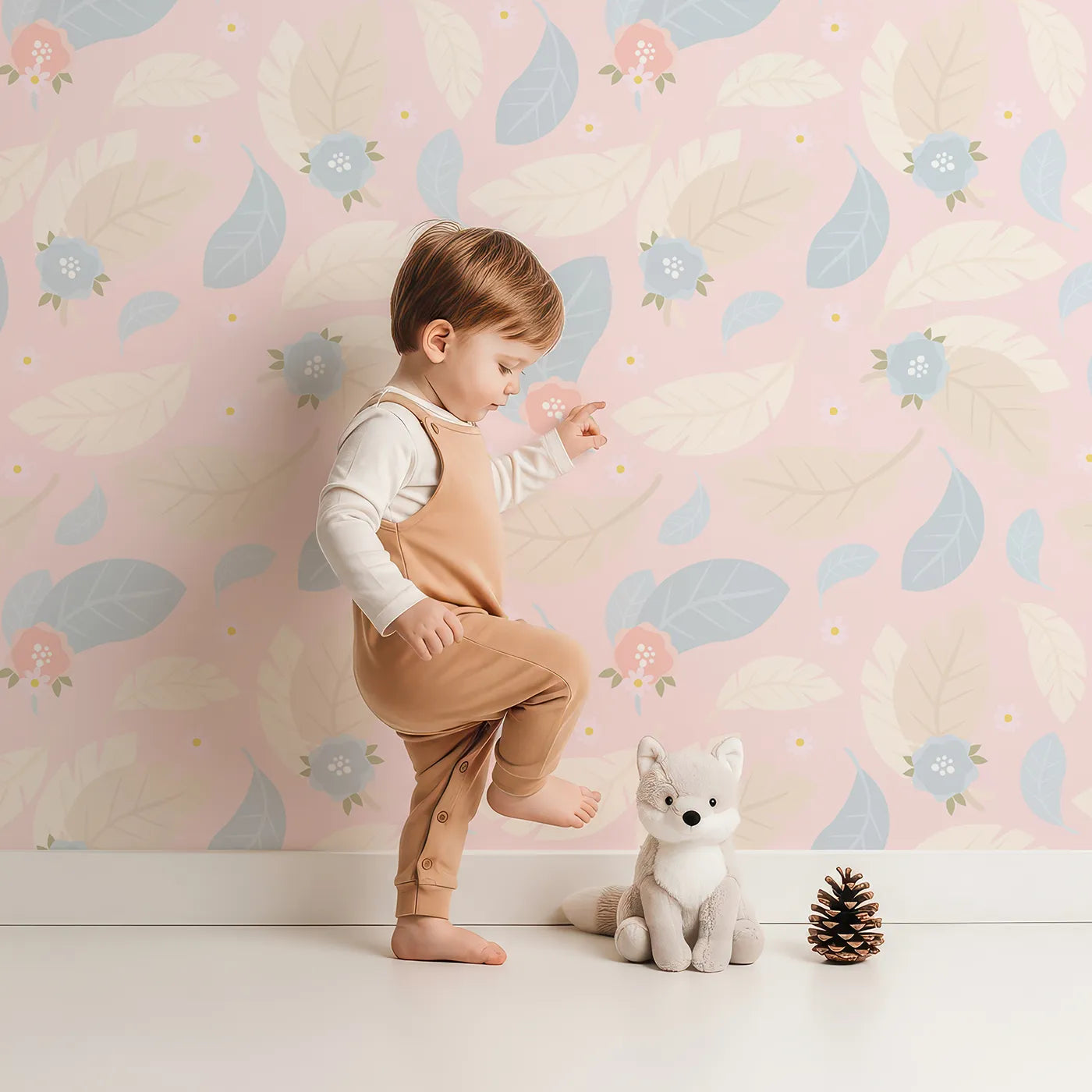 Lovely child standing in front of Whimsy Tots Whispering Petal Leaves Wallpaper in Blush Sky Pink with leaf, flower, petal in design.
