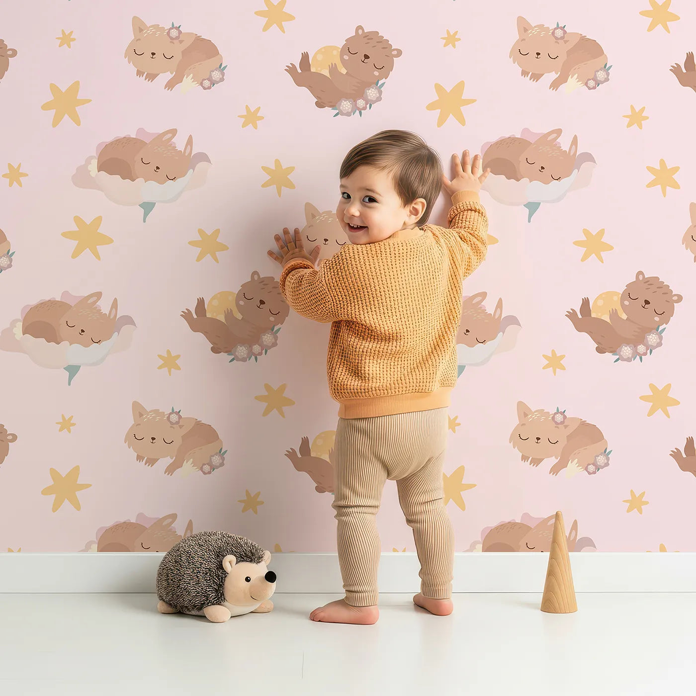 Lovely child standing in front of Whimsy Tots Woodland Nap Parade Wallpaper in Soft Mint Green with bear, bunny, fox, flower, star in design.