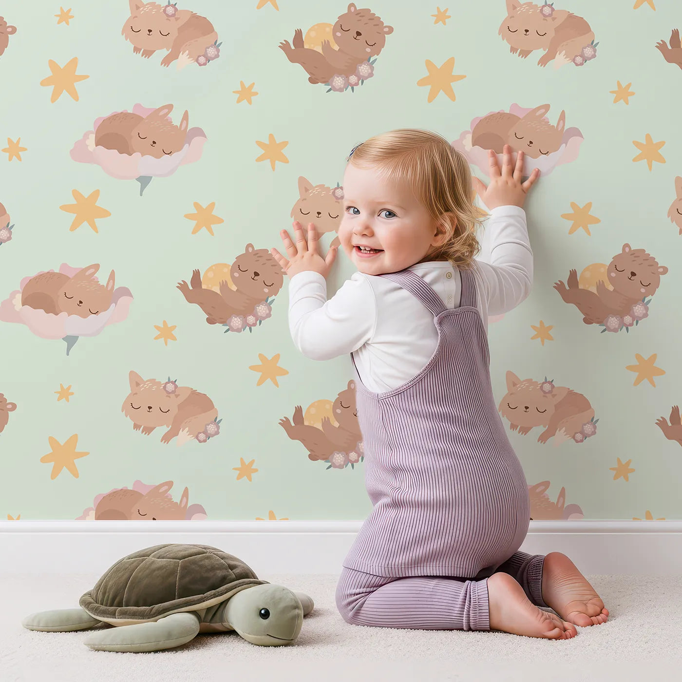 Lovely child standing in front of Whimsy Tots Woodland Nap Parade Wallpaper in Buttercream with bear, bunny, fox, flower, star in design.