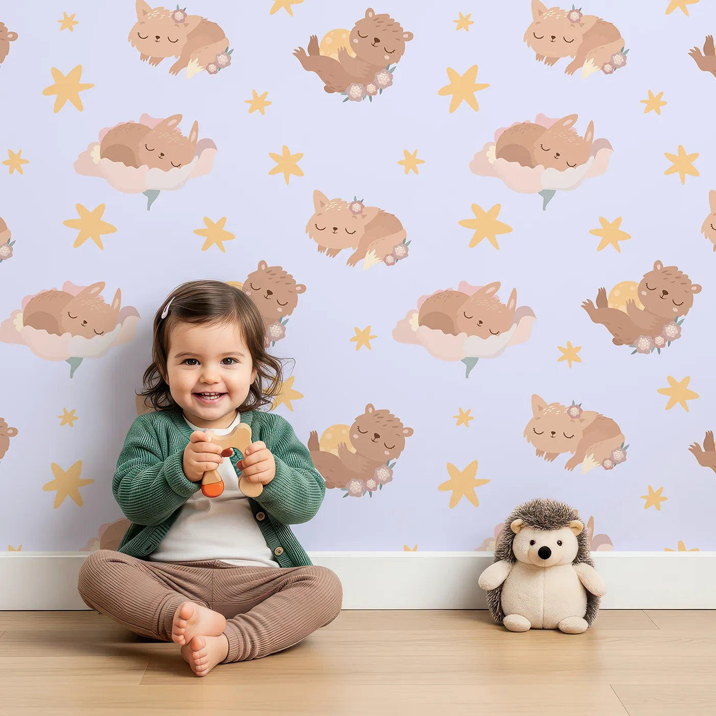 Lovely child standing in front of Whimsy Tots Woodland Nap Parade Wallpaper in Lavender Mist with bear, bunny, fox, flower, star in design.