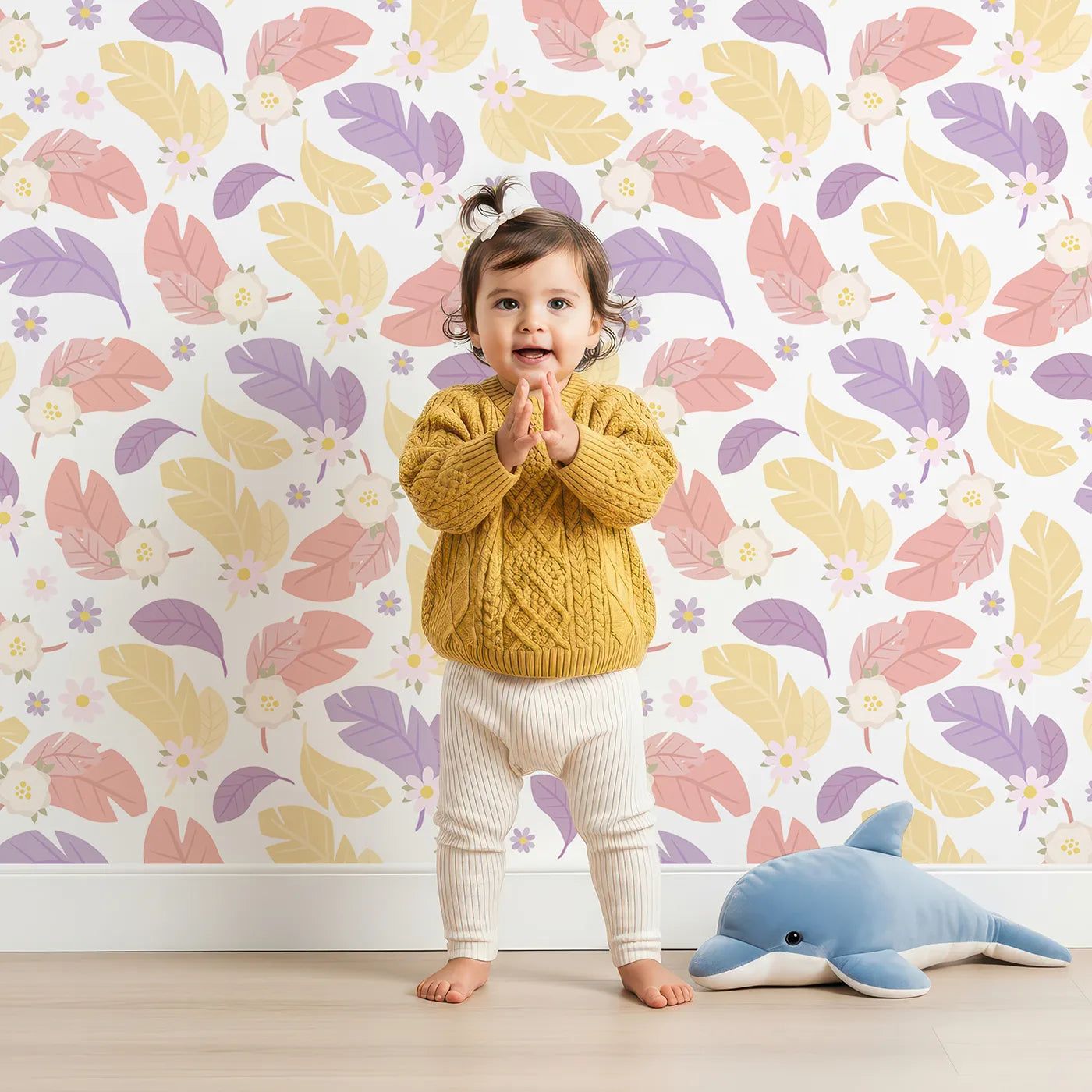Lovely child standing in front of Whimsy Tots Pastel Feather Garden Wallpaper in Spring Mix with flower, leaf, feather, petal in design.
