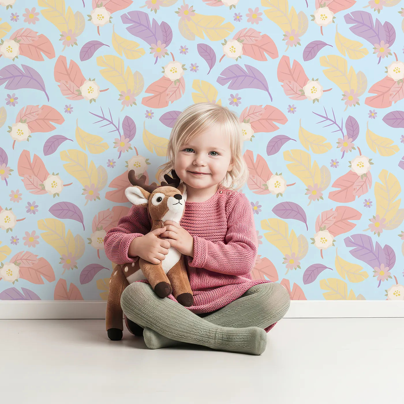 Lovely child standing in front of Whimsy Tots Pastel Feather Garden Wallpaper in Blue Skies with flower, leaf, feather, petal in design.