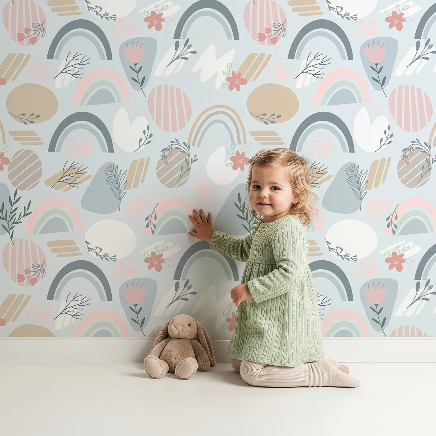Lovely child standing in front of Whimsy Tots Pastel Bloom Rainbow Wallpaper in Sky Blue with rainbow, flower, leaf, petal, stripe in design.