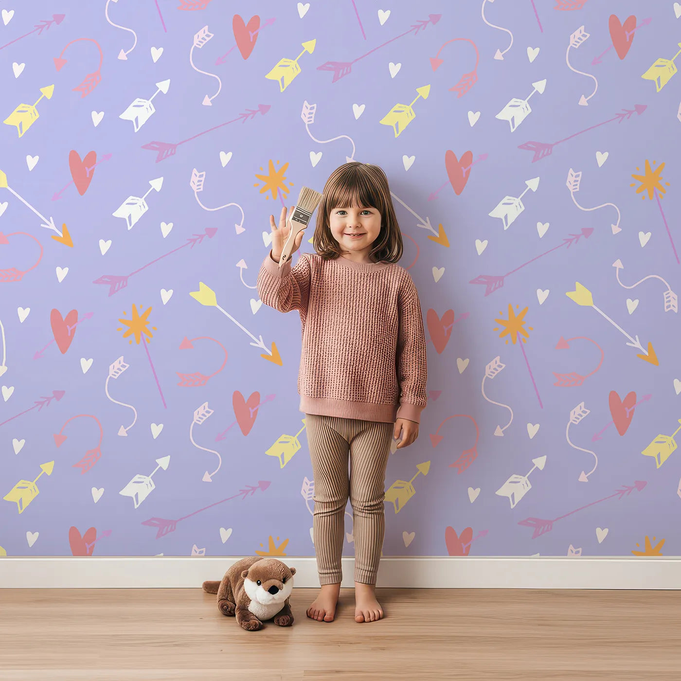 Lovely child standing in front of Whimsy Tots Cupids Arrow Parade Wallpaper in Lavender Pop with arrow, heart, star in design.