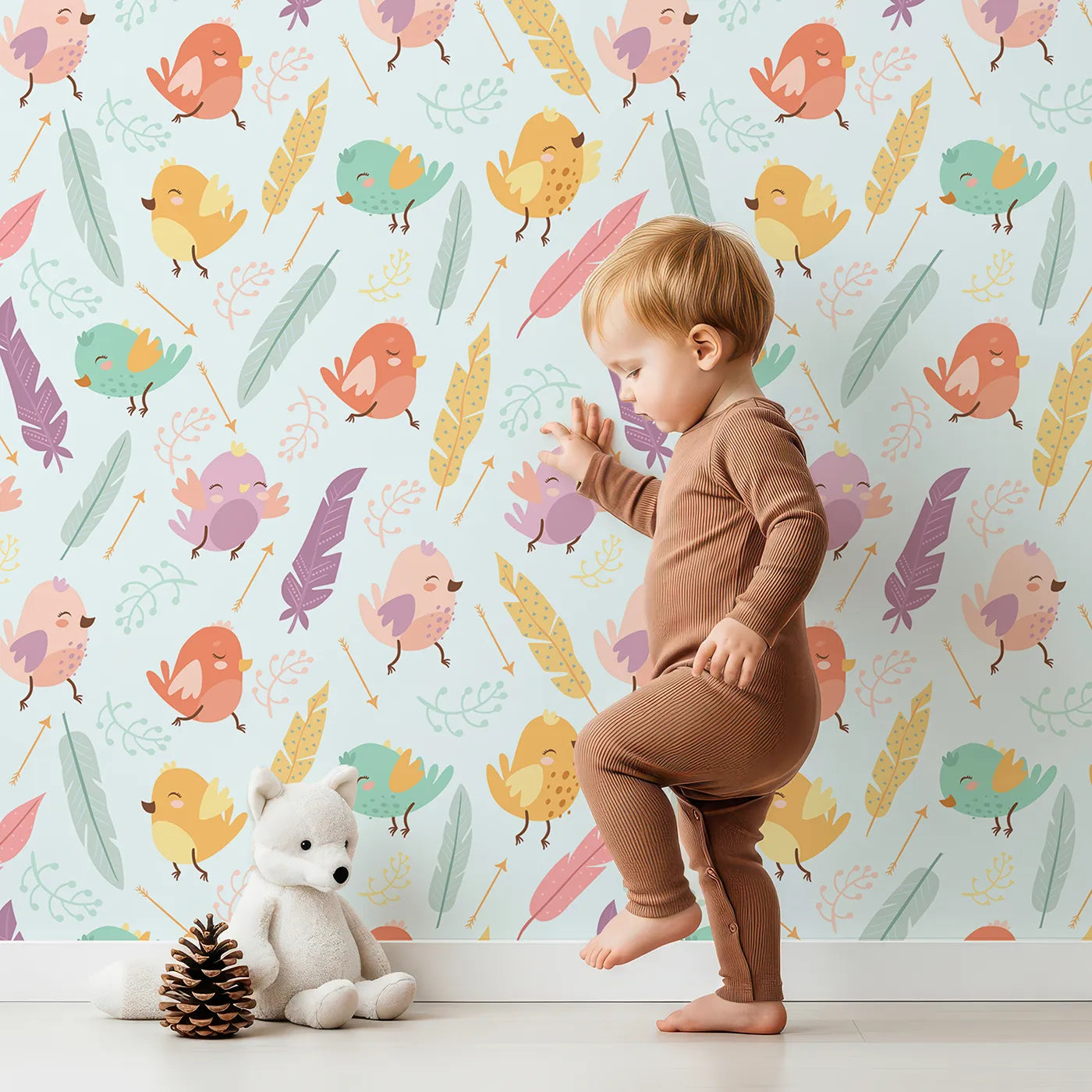 Lovely child standing in front of Whimsy Tots Feathered Joy Parade Wallpaper in Sky Mint with bird, feather, sprig, arrow in design.