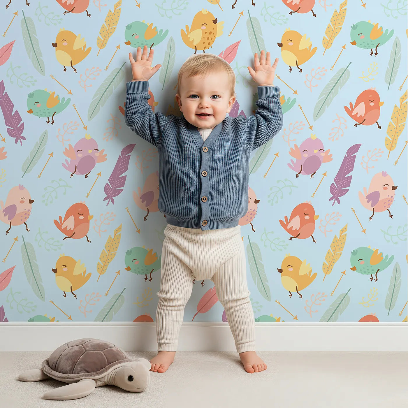 Lovely child standing in front of Whimsy Tots Feathered Joy Parade Wallpaper in Sky Blue with bird, feather, sprig, arrow in design.