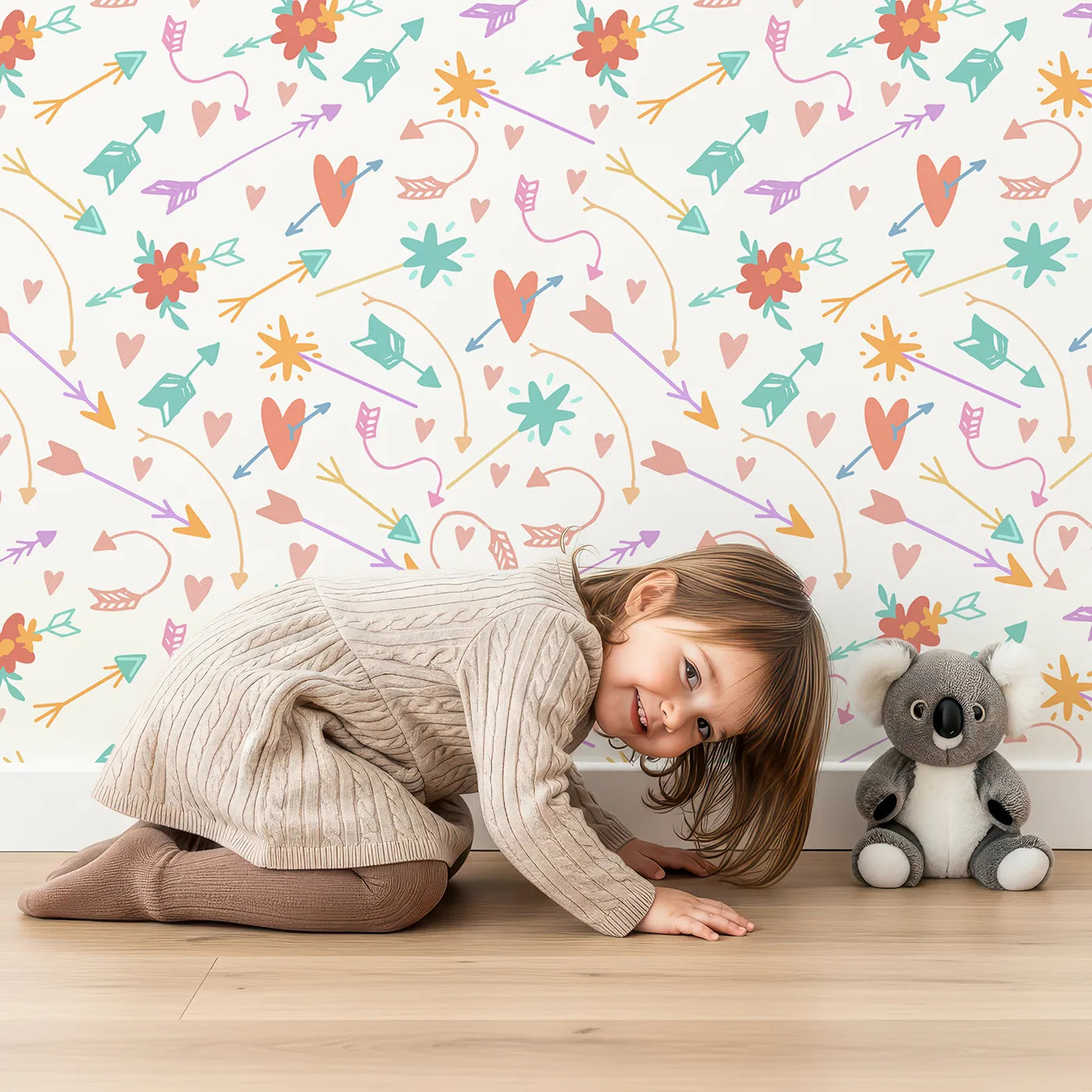 Lovely child standing in front of Whimsy Tots Love and Arrows Bloom Parade Wallpaper in Cream Blush with arrow, heart, flower, burst in design.