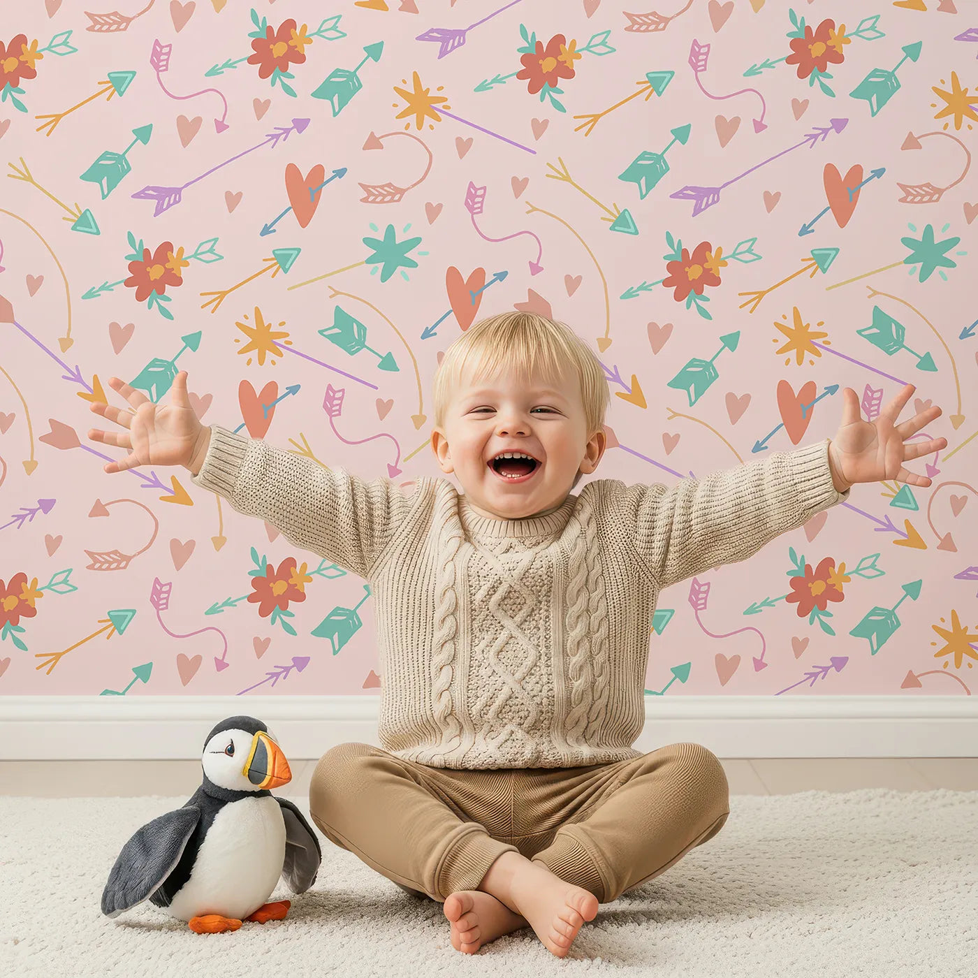 Lovely child standing in front of Whimsy Tots Love and Arrows Bloom Parade Wallpaper in Blush Pink with arrow, heart, flower, burst in design.