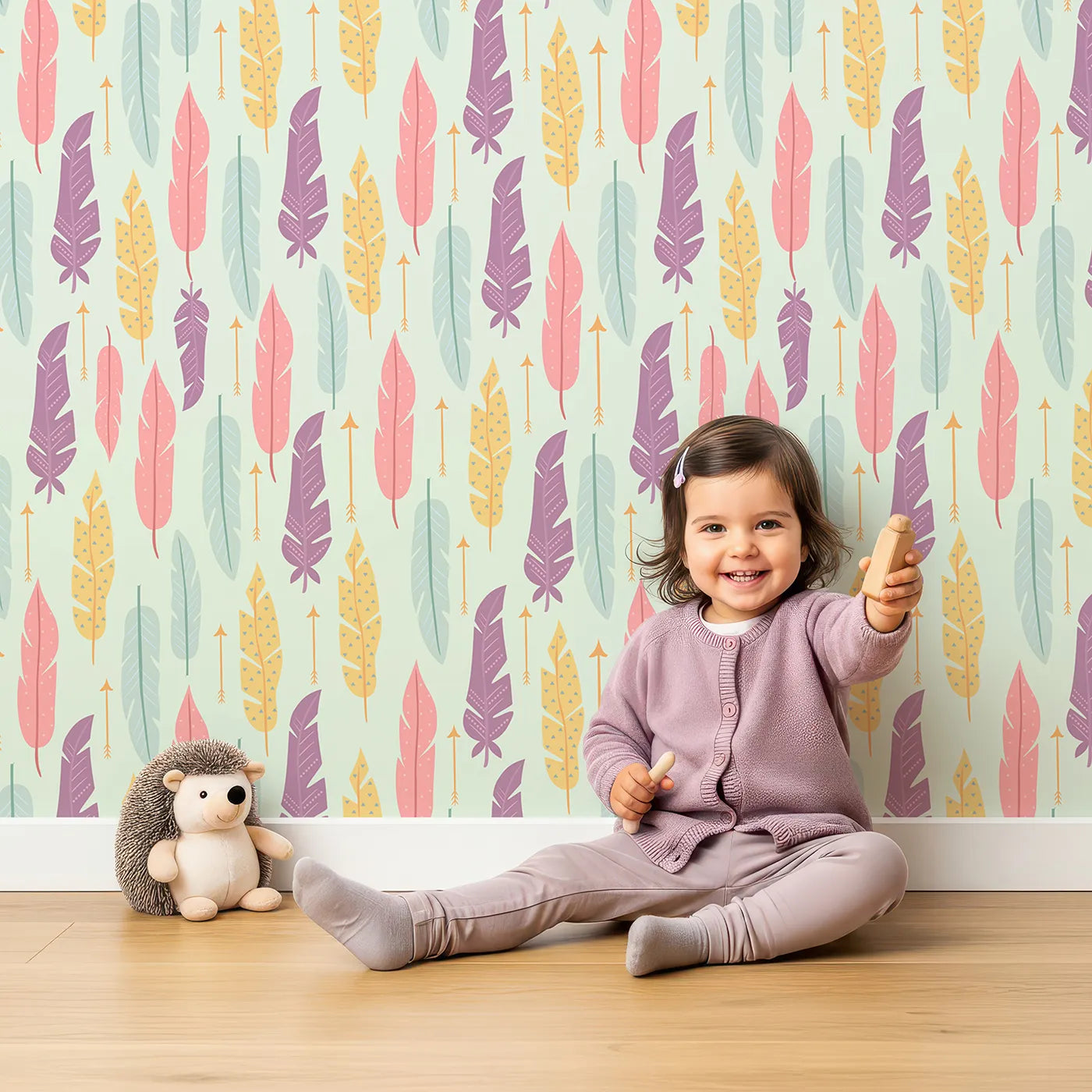 Lovely child standing in front of Whimsy Tots Feather and Arrow Meadow Parade Wallpaper in Soft Mint Green with feather, arrow, leaf in design.